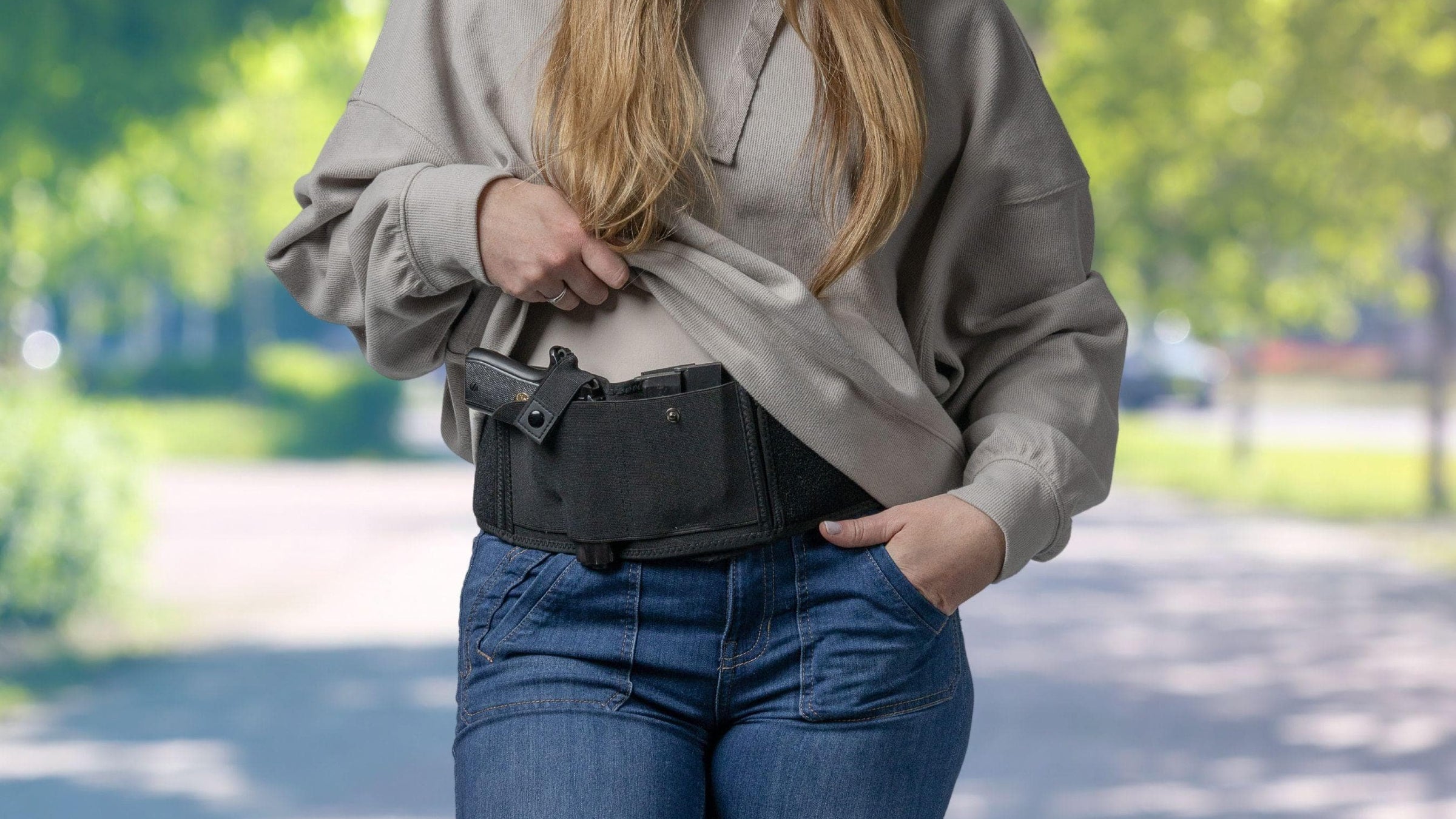 Woman holding a gun in a belt holster outdoors